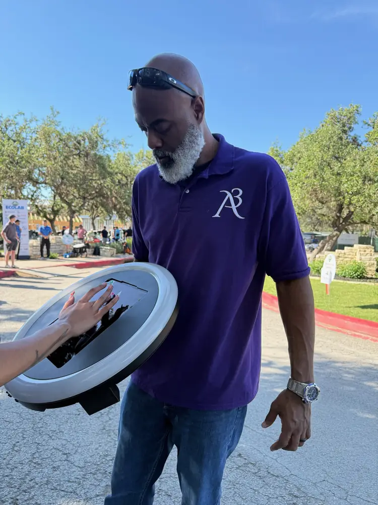 A3 Rentals attendant in a purple polo holding the ring-light booth at an outdoor golf event