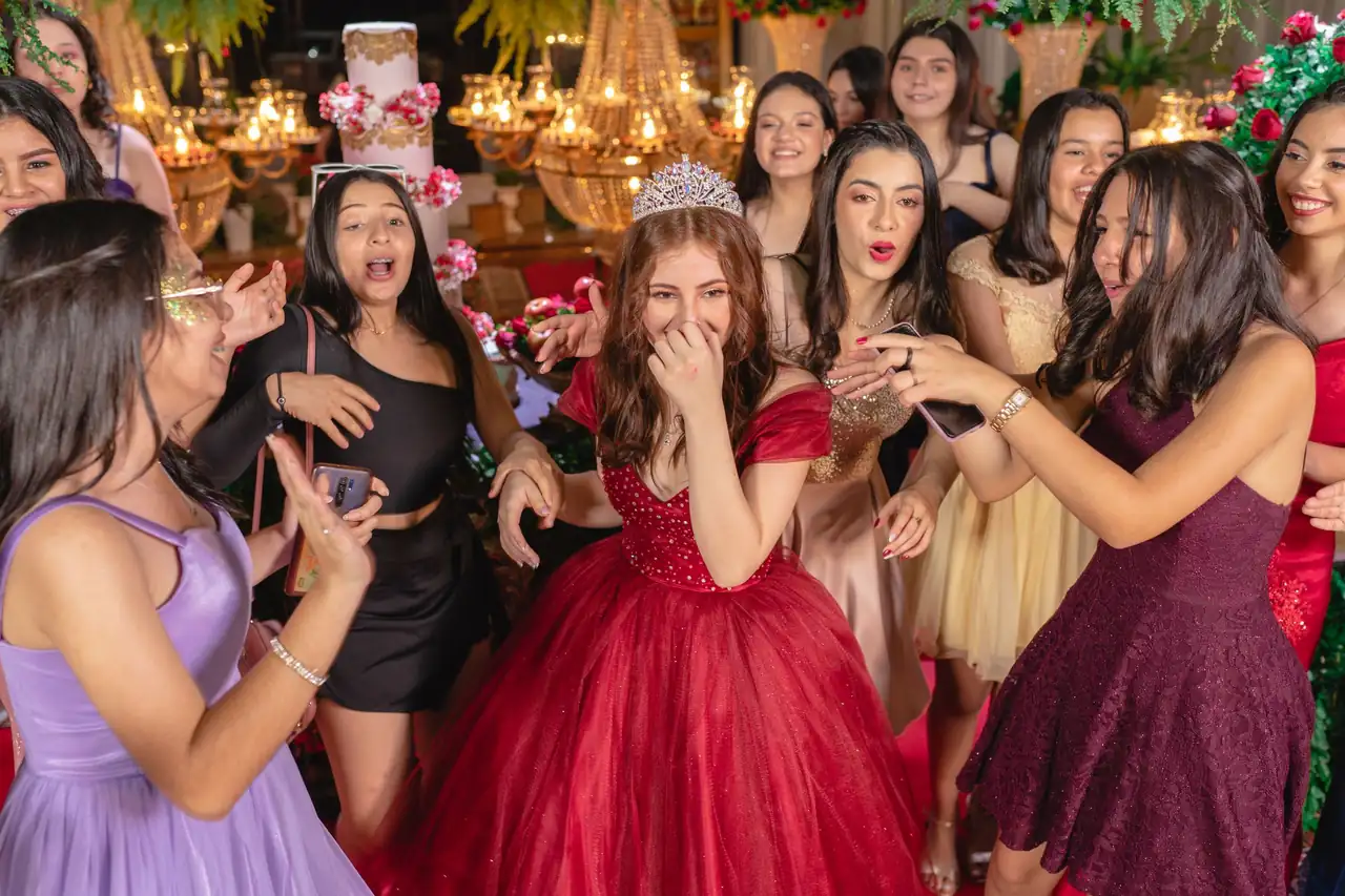 Quinceañera in a red gown celebrating with friends in colorful dresses